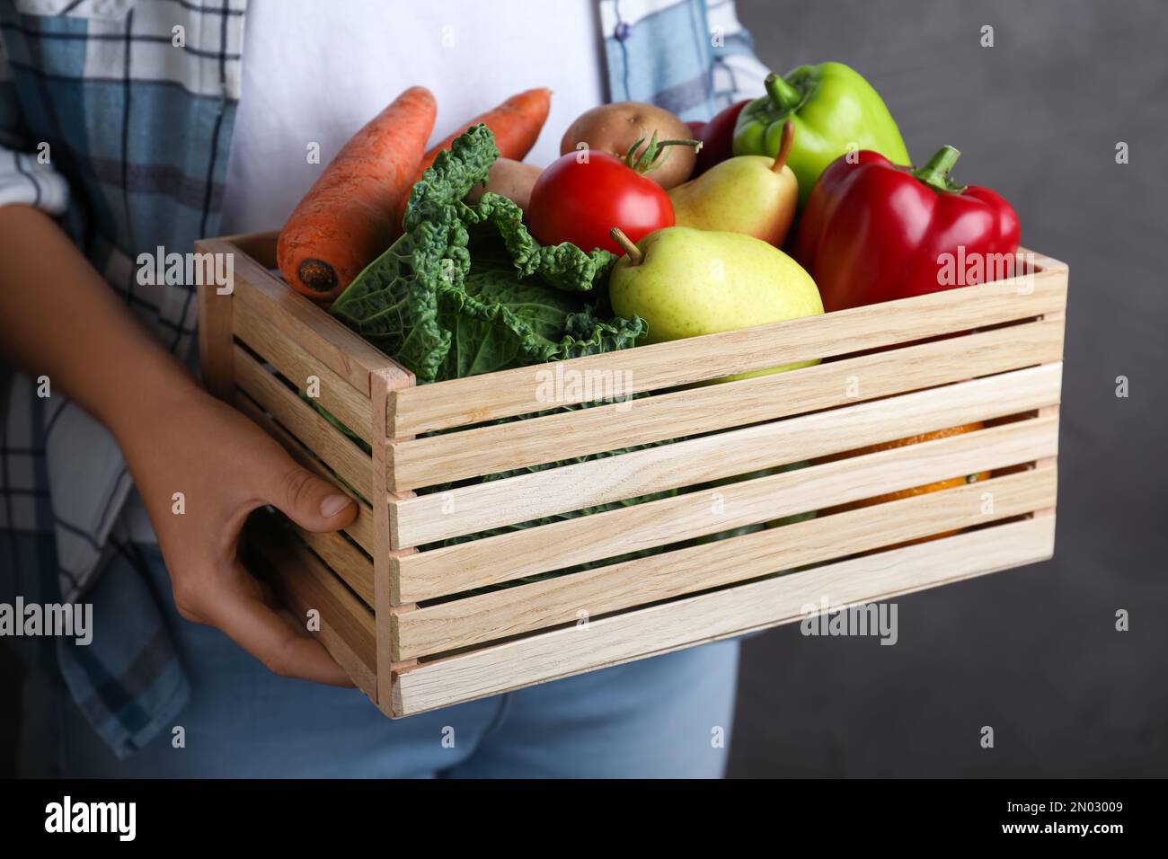Farmer holding wooden crate filled with fresh vegetables and fruits on ...