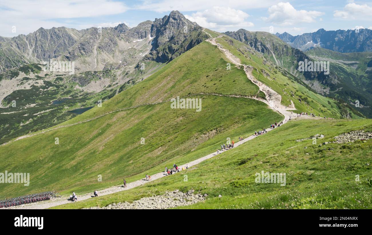 Crowds of tourists walking on the trail towards a prominent mountain in the background, Poland, EU Stock Photo