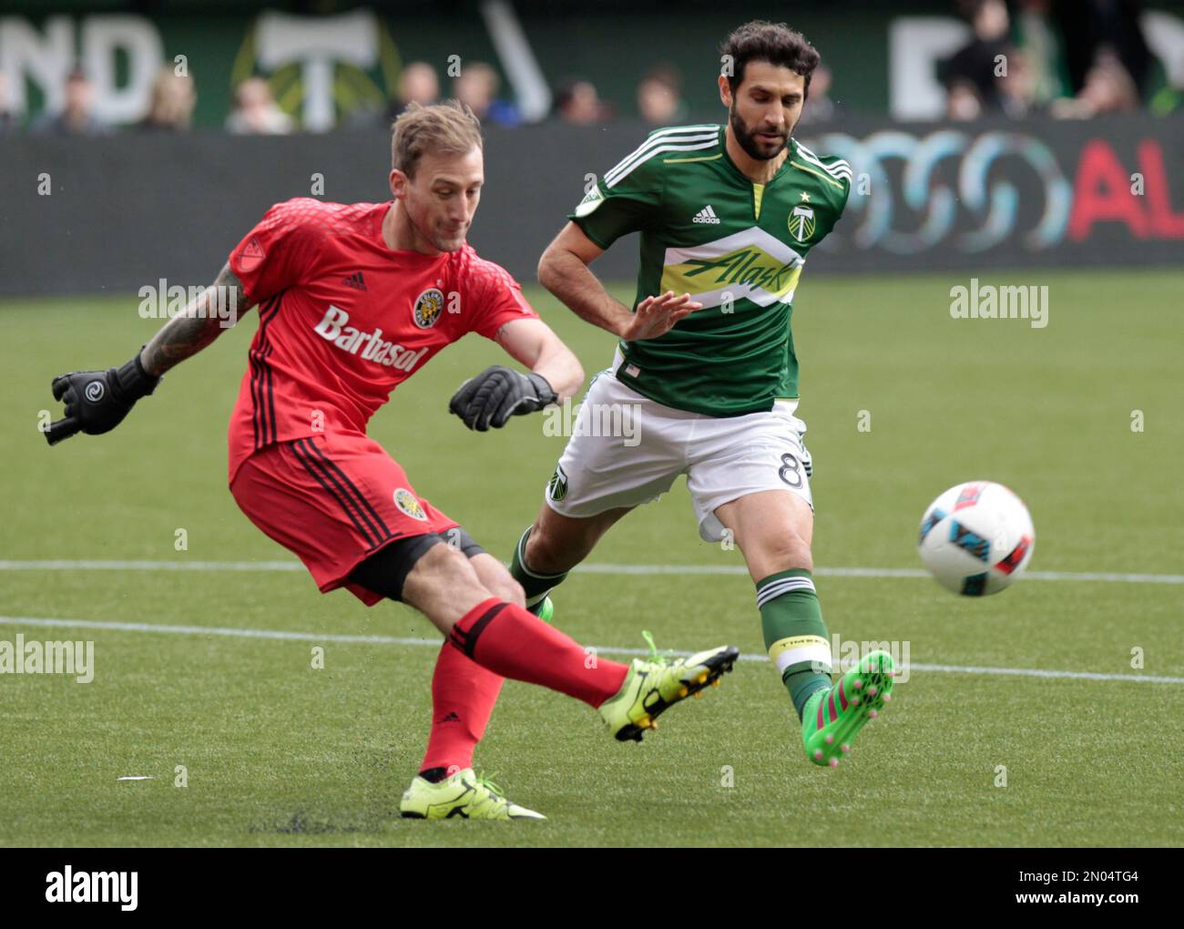 Columbus Crew goalkeeper Steve Clark, left, clears the ball as Portland