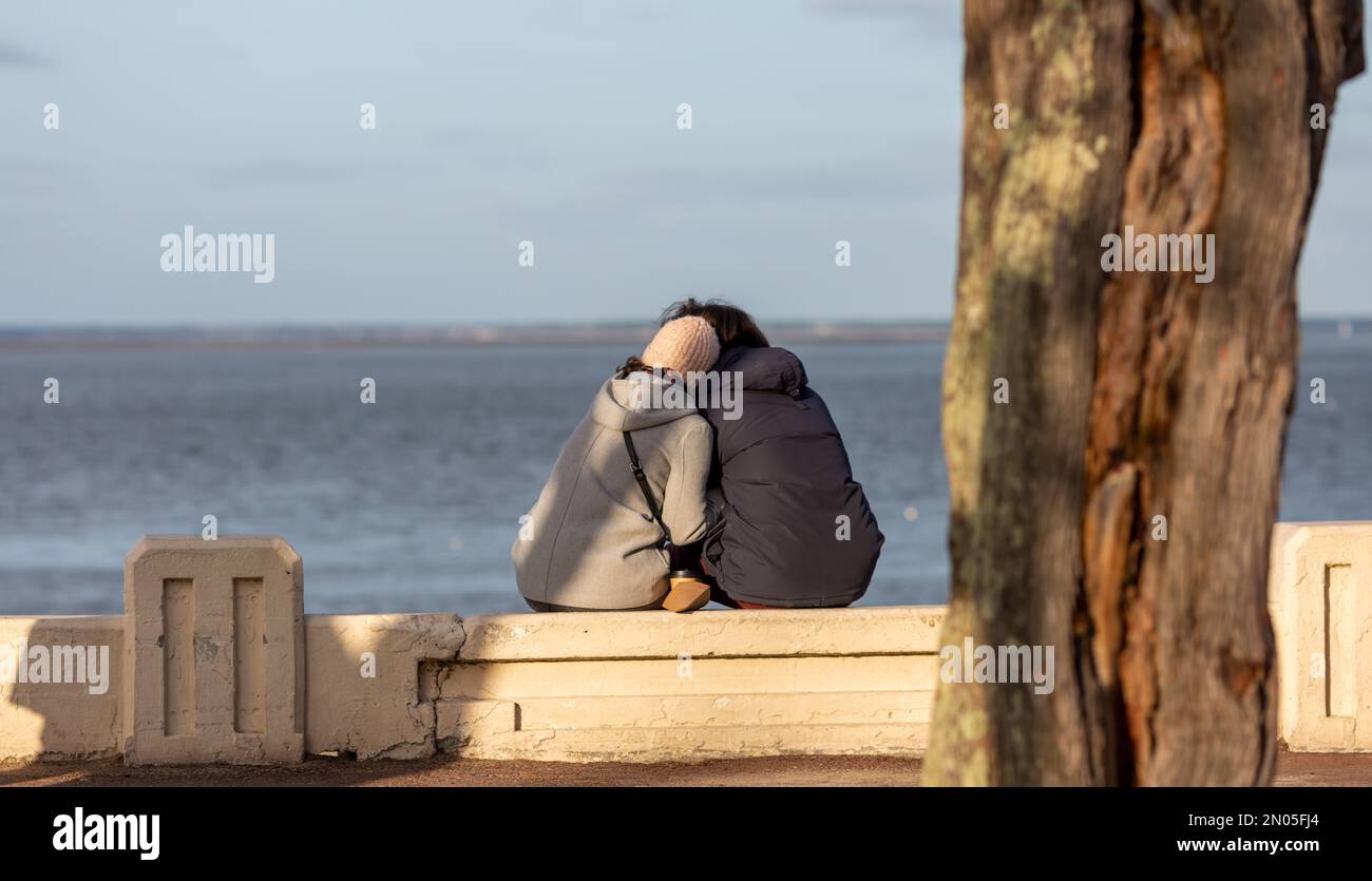 couple sitting on a bench looking at the sea Stock Photo - Alamy