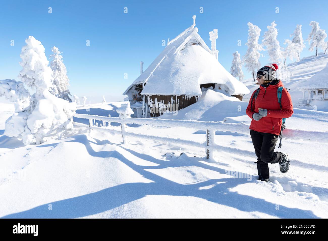Beautiful scenery after heavy snowfall on velika planina alpine pasture fairytale winter landscape, snowy trees, tourist woman and snowy cottage Stock Photo