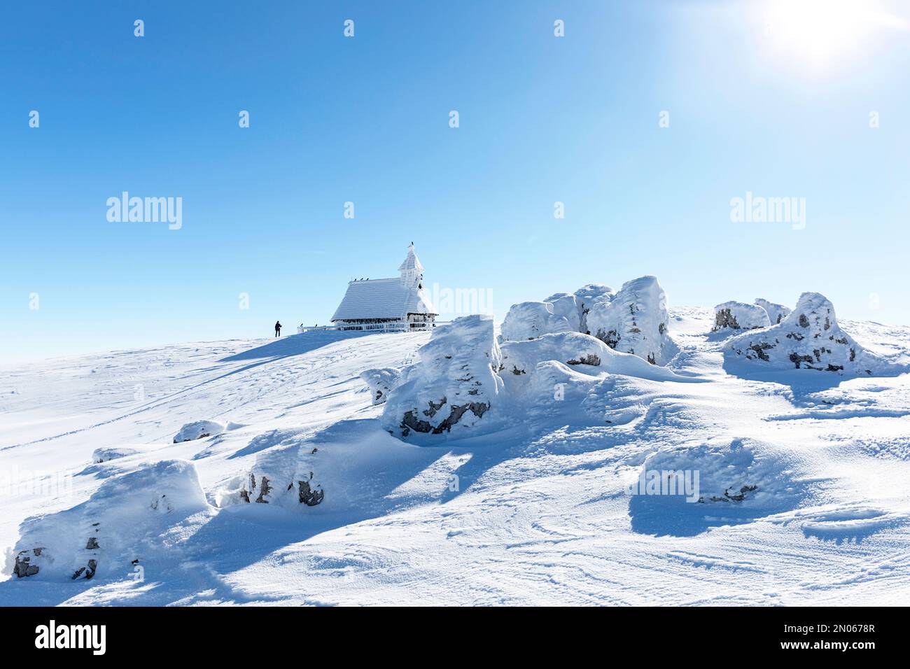Hiker, tourist stopping at the spectacular frozen Chapel of Mary of the Snows on Velika planina Alpine pasture, winter fairytale landscape, Slovenia Stock Photo