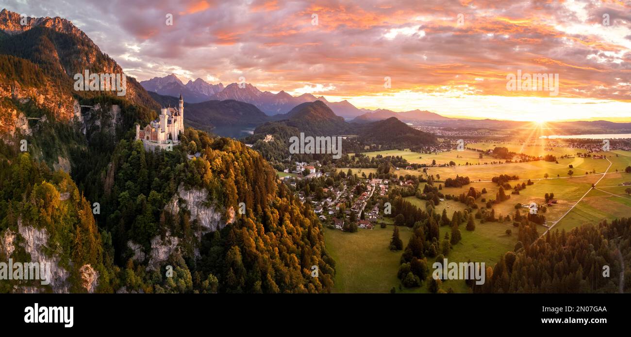Romantic colorful landscape with famous German castle 'Schloss Neuschwanstein' from a distance, aerial view of the mountains and the valley at sunset Stock Photo