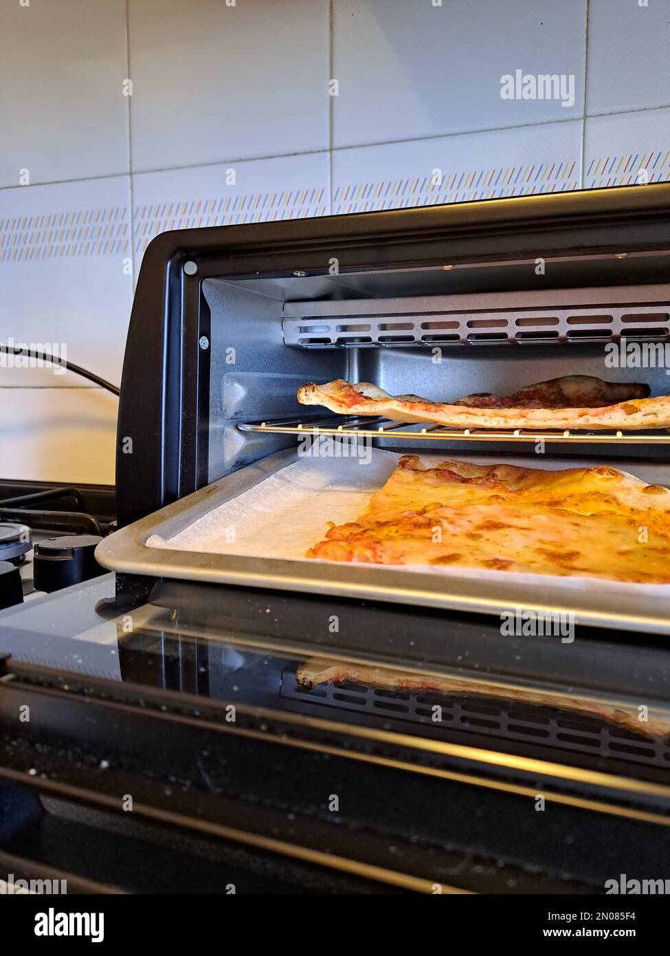 Slice of cheese pizza closeup real life in the kitchen, reheat in the electric oven Stock Photo