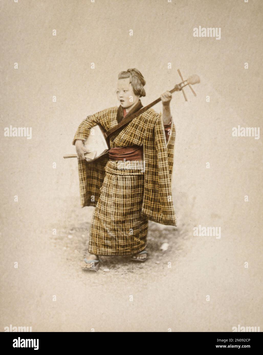 A photograph of a Japanese woman playing music. Published in Views & Costumes of Japan by Stillfried and Andersen (Yokohama, 1877). Stock Photo