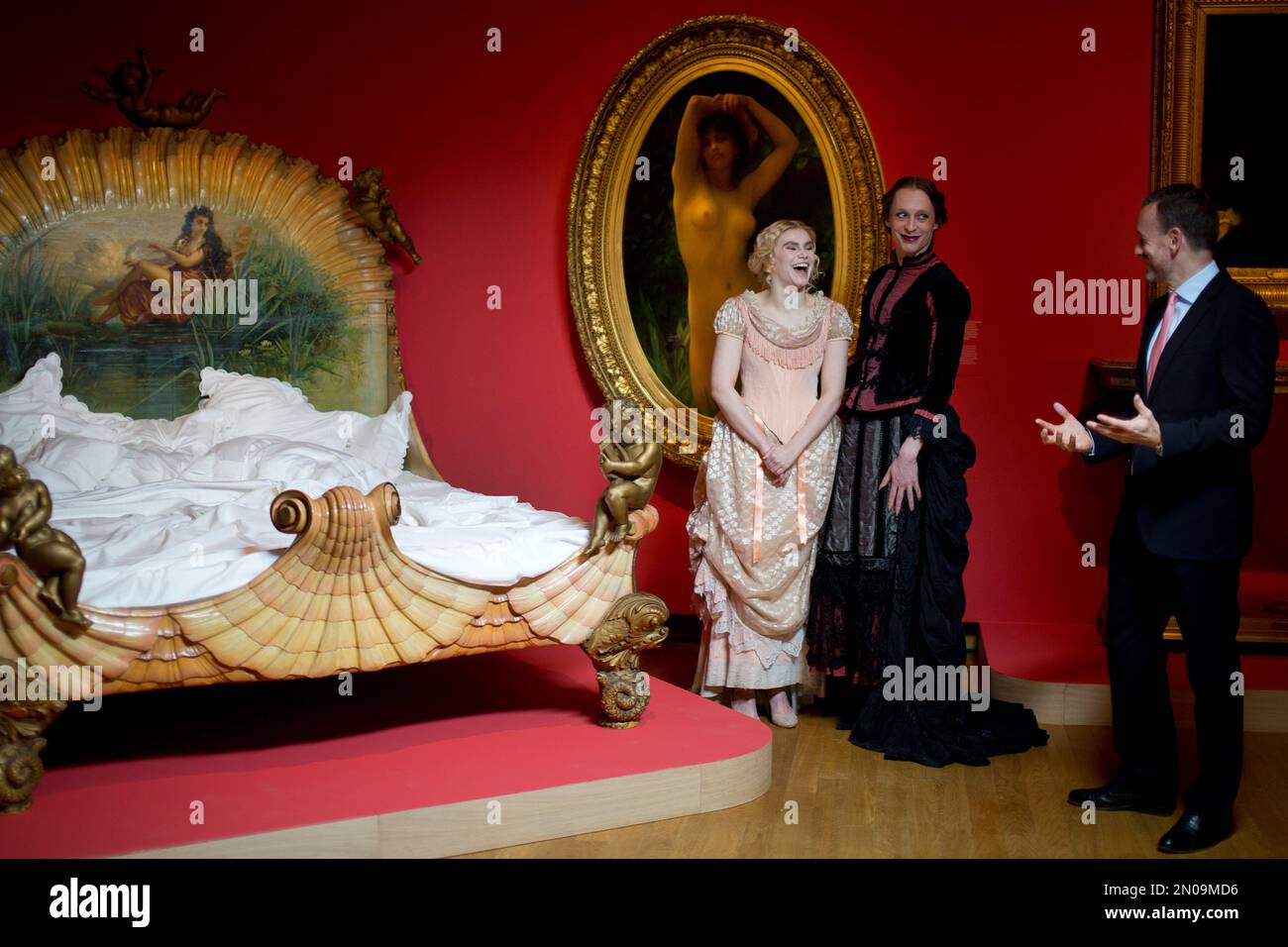 Museum director Axel Ruger jokes with models who pose next to a 19th ...