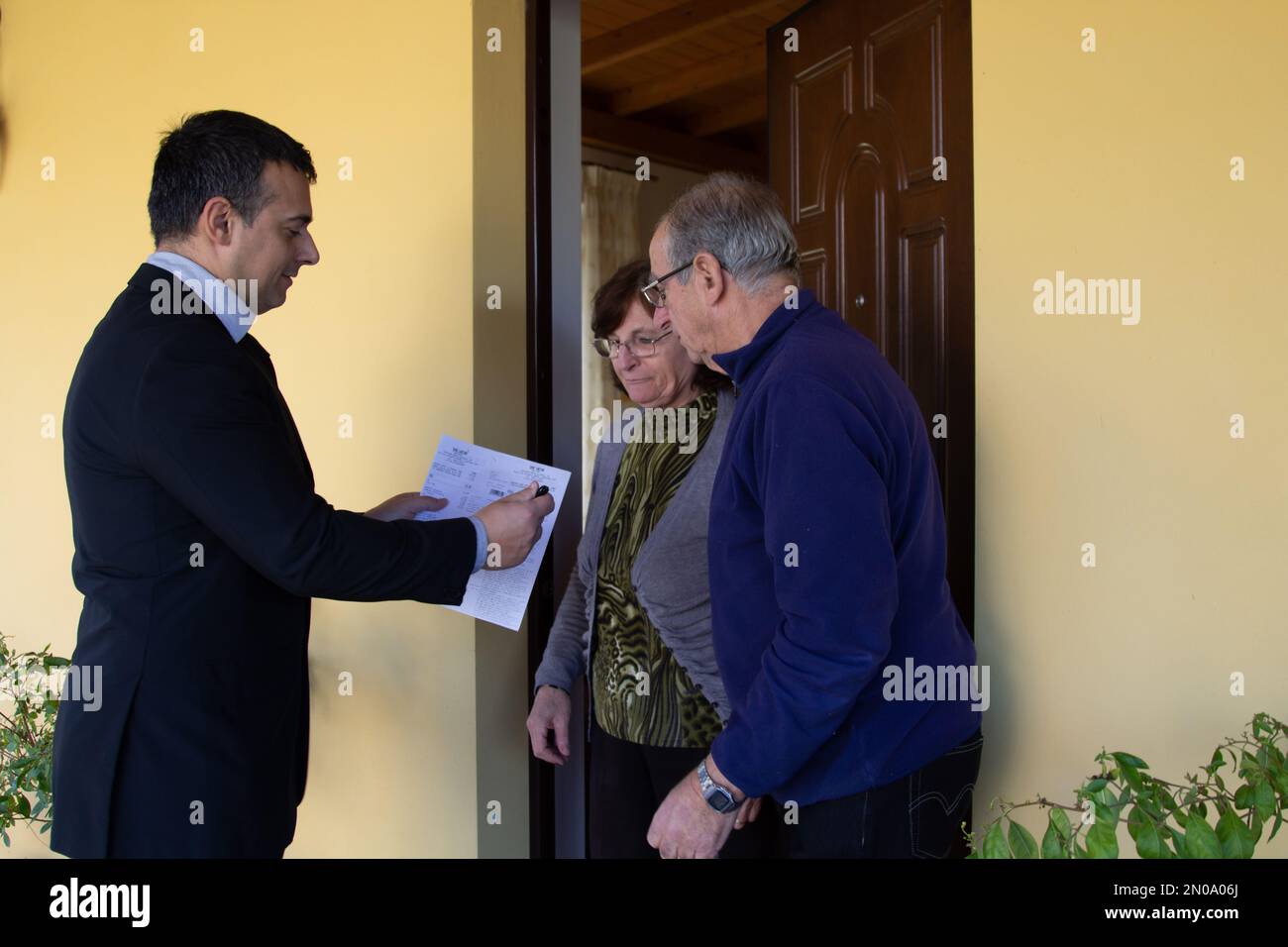 Elegant smiling man knocking door to door to explain the electoral campaign plan. Request for votes in the next elections and on the candidate to vote Stock Photo