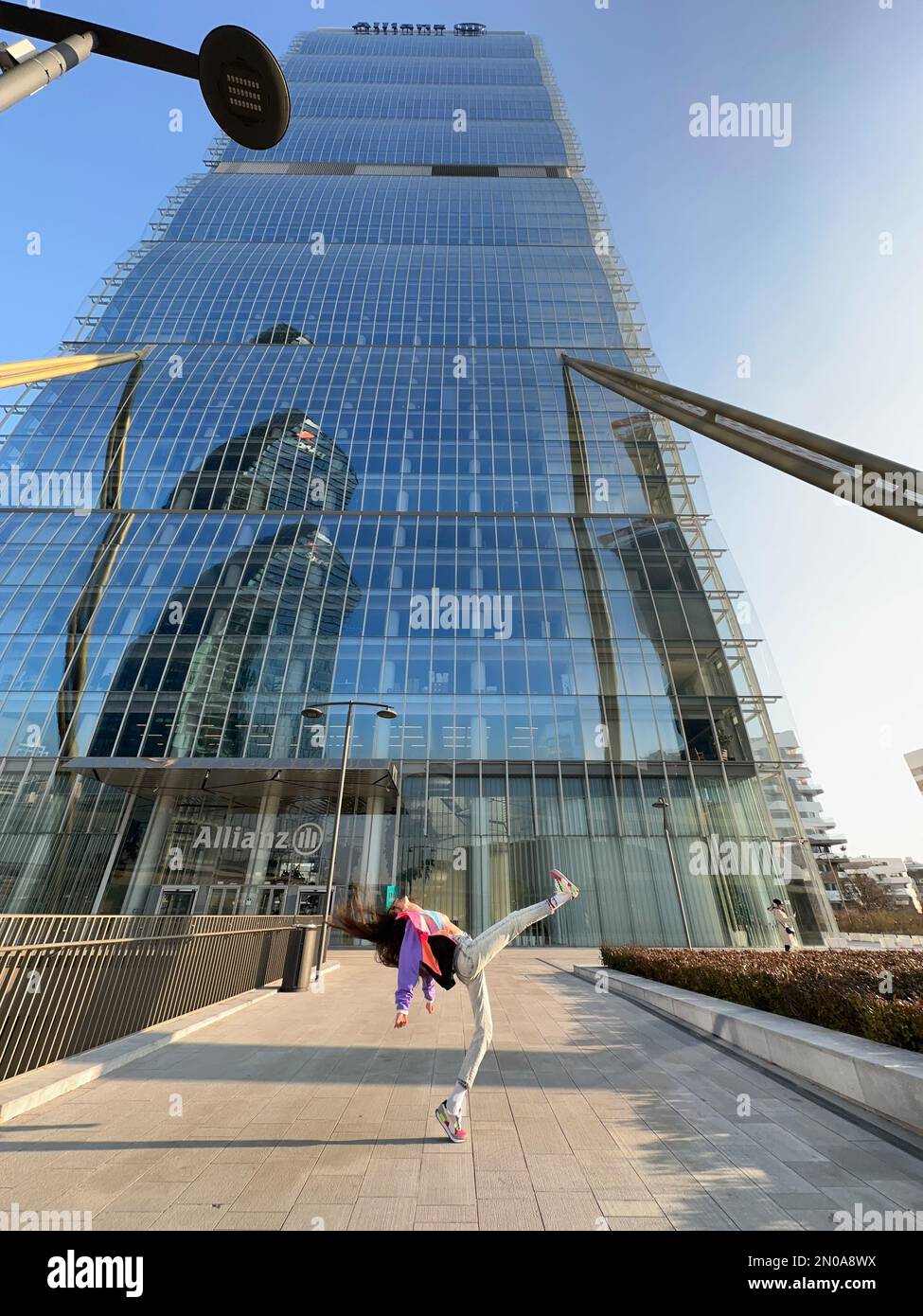 a fantastic image of a young girl, dancing in bright fashionable clothes, under the CityLife Allianz tower, Isozaki tower, CityLife, Milan, Italy Stock Photo
