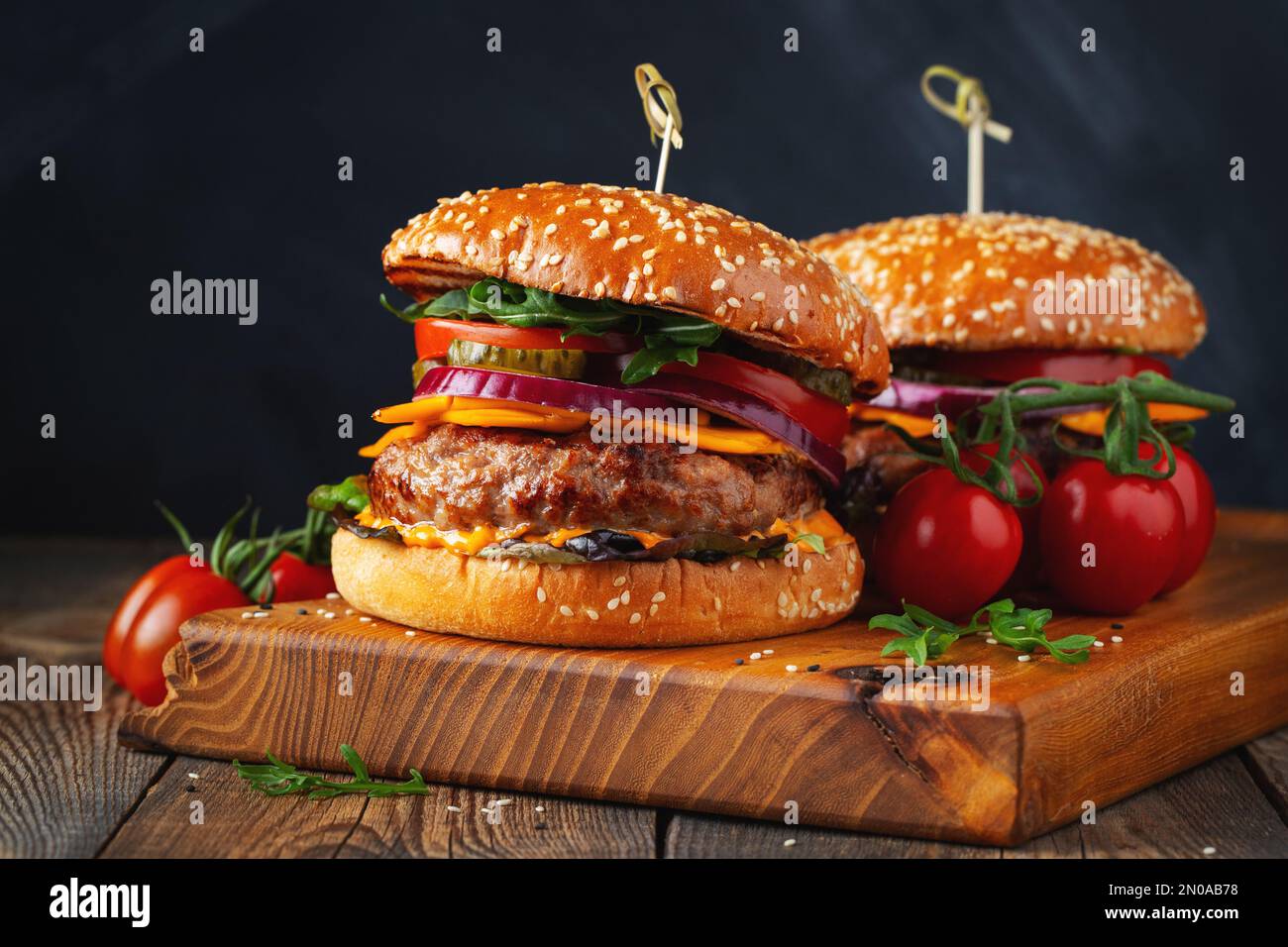 Two delicious homemade burgers of beef, cheese and vegetables on an old