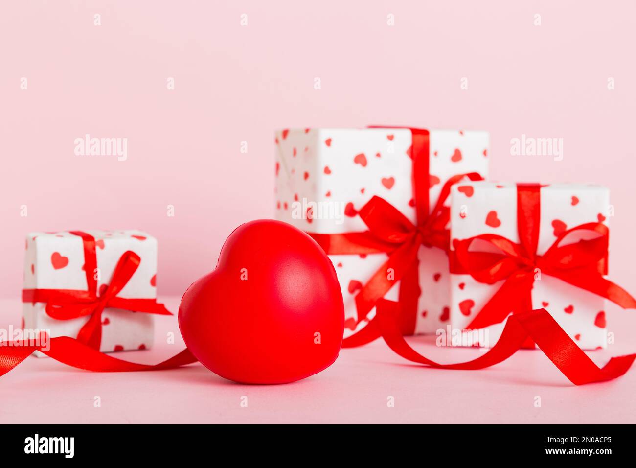 gift box with red bow and red heart on colored background. Perspective ...