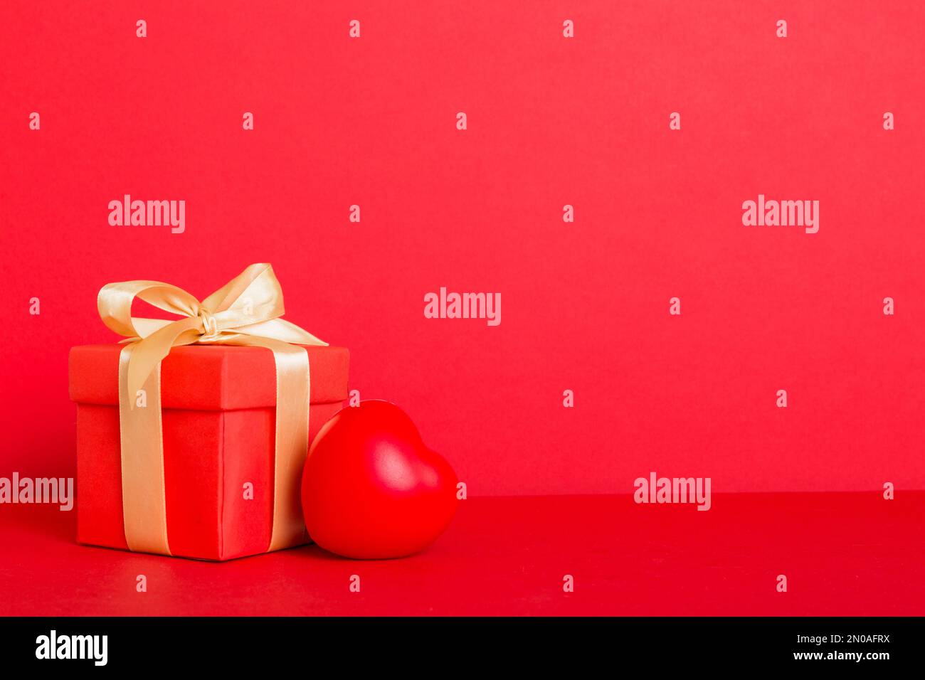 gift box with red bow and red heart on colored background. Perspective ...