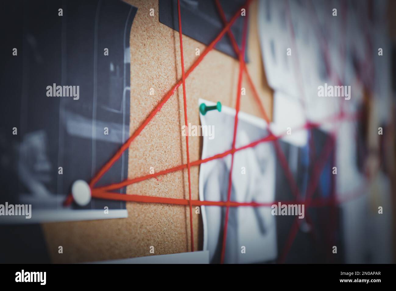 Detective board with crime scene photos and red threads, closeup Stock Photo