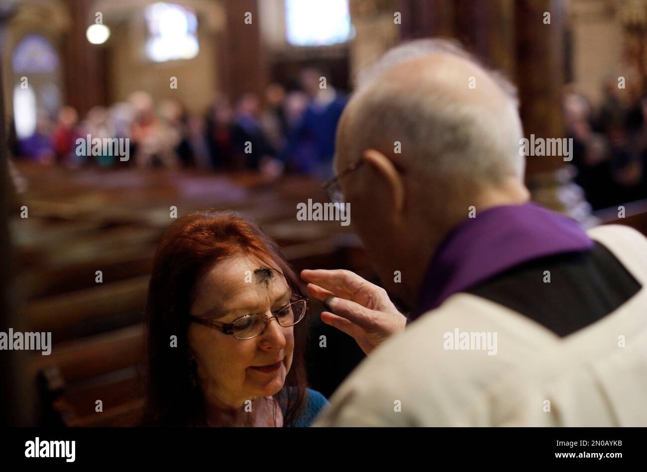 A churchgoer receives ashes on her forehead at an Ash Wednesday Mass at