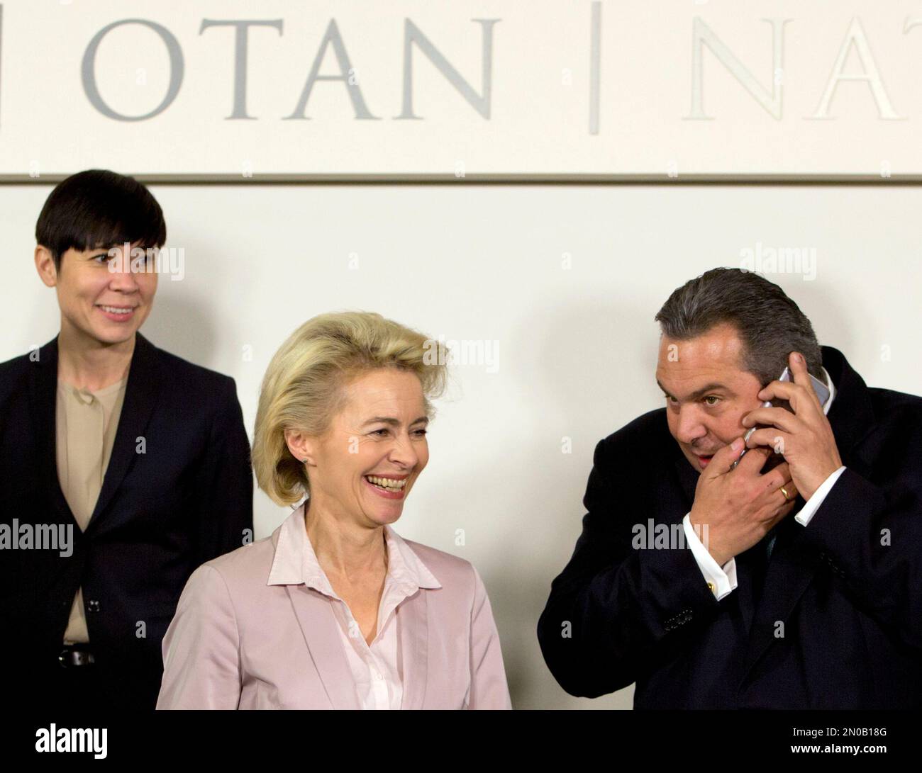 Greek Defense Minister Panos Kammenos, right, speaks on his cellphone  during a group photo of NATO defense ministers at NATO headquarters in  Brussels on Wednesday, Feb. 10, 2016. NATO and the European