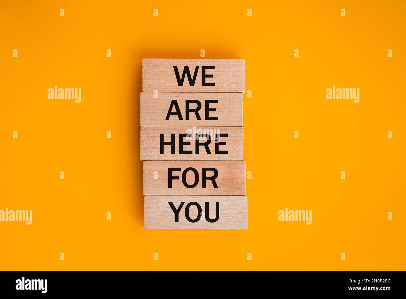we are here for you, Written on wooden blocks, words to live by, Business idea. invitation to cooperation, support concept, beautiful yellow backgroun Stock Photo