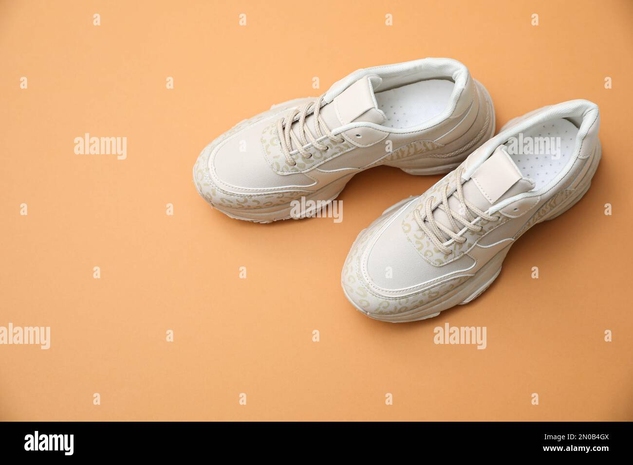 Stylish white shoes on pale orange background Stock Photo Alamy