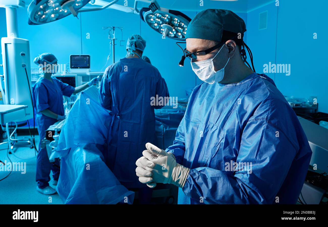 Experienced surgeon psychologically prepares himself for surgical operation standing in operating theater with modern medical equipment Stock Photo
