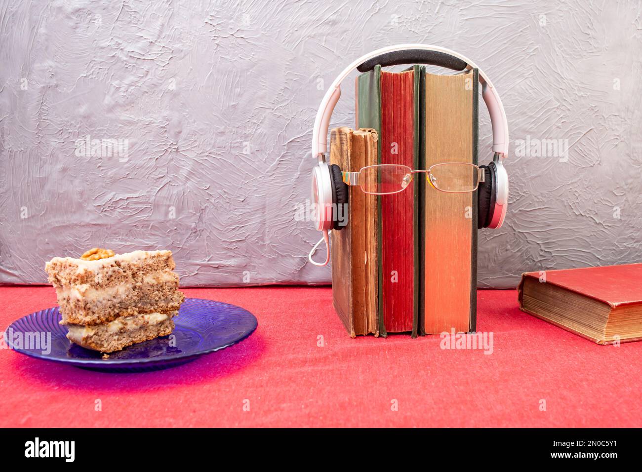 vintage books, and a layered cake on a blue glass plate, Reading at breakfast  concept Stock Photo