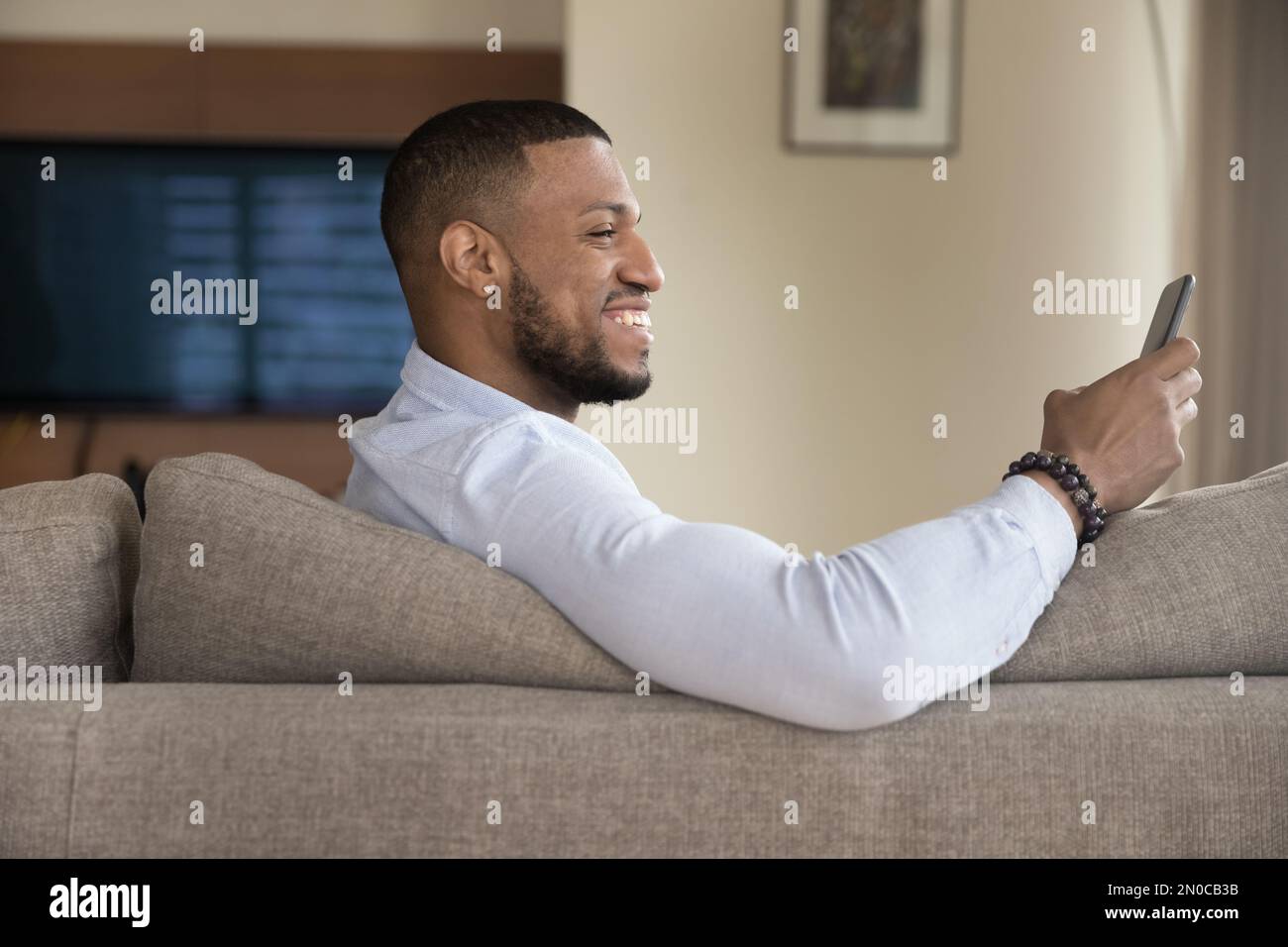Cheerful excited handsome Black guy using mobile phone Stock Photo