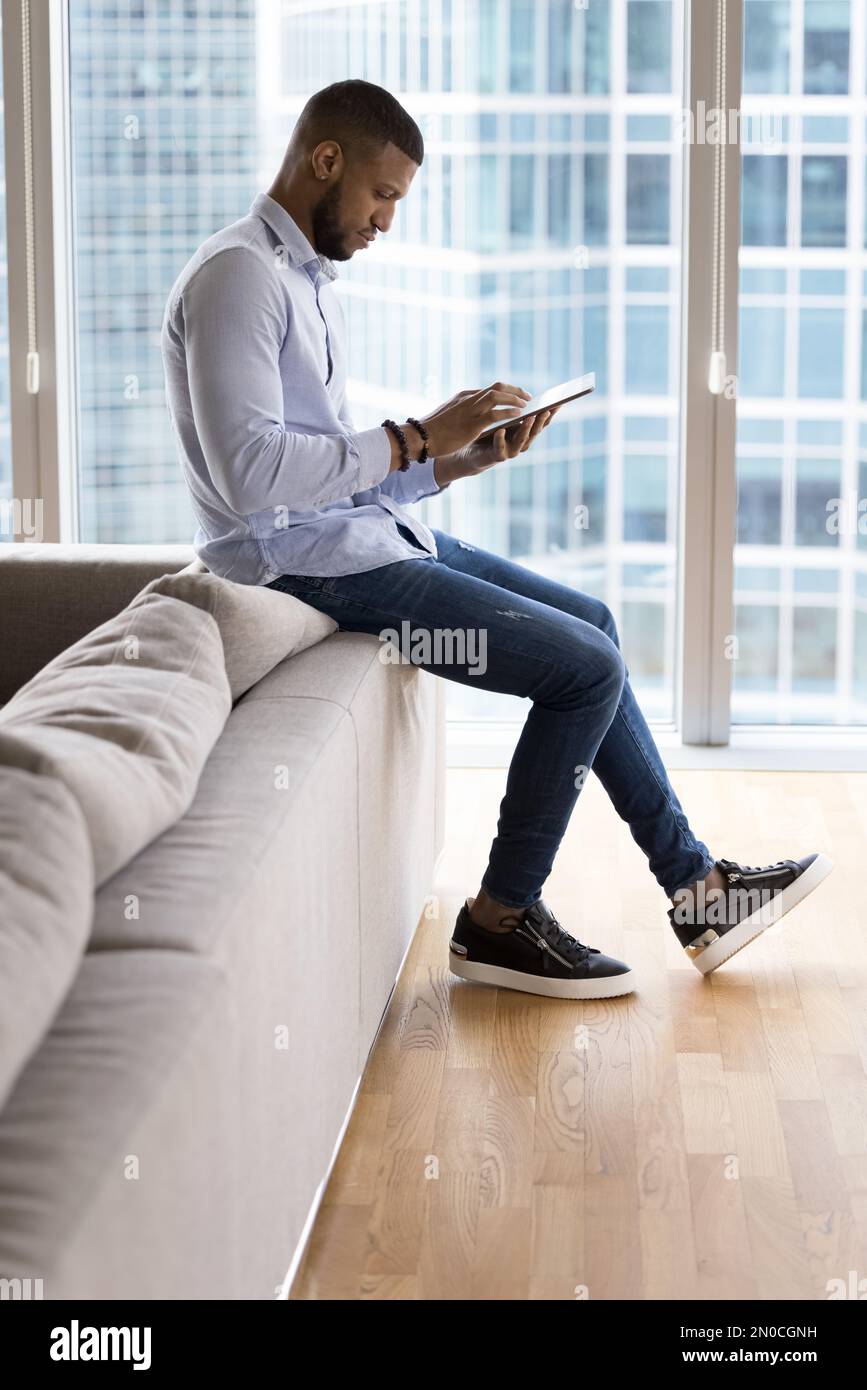 Focused young entrepreneur man using tablet at home Stock Photo