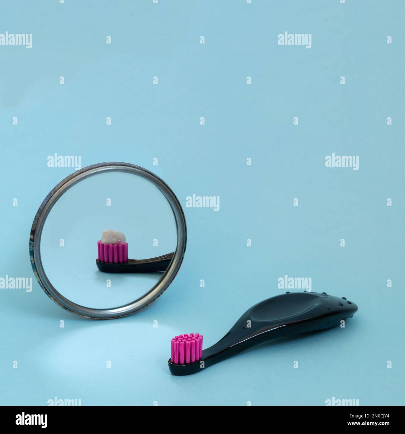 Kids toothbrush with toothpaste mirorr reflection. International day of dentist. Creative concept of daily morning routine. Copy space, square format Stock Photo
