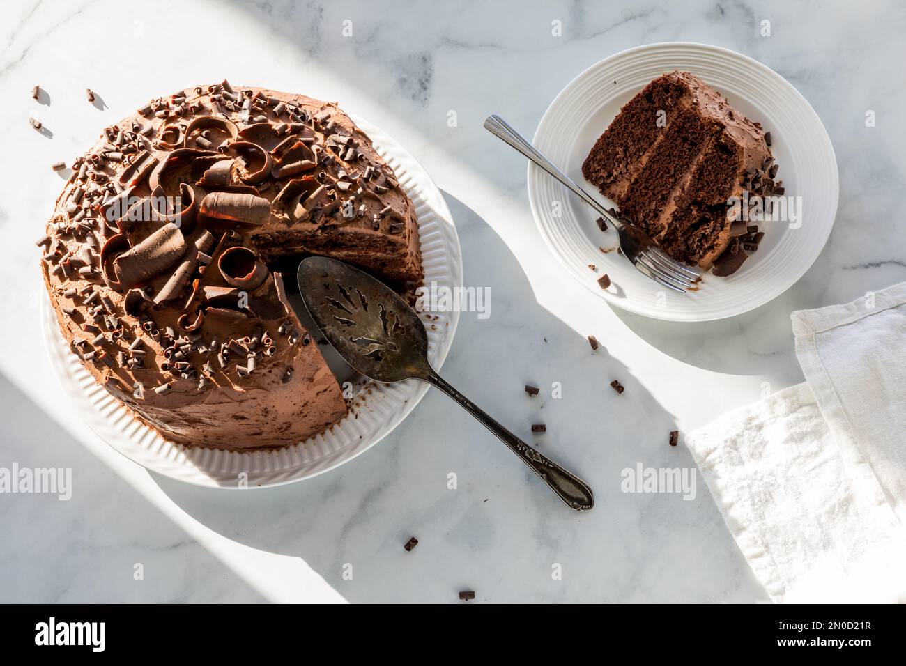 A chocolate cake decorated with chocolate curls, sitting in bright sunlight. Stock Photo