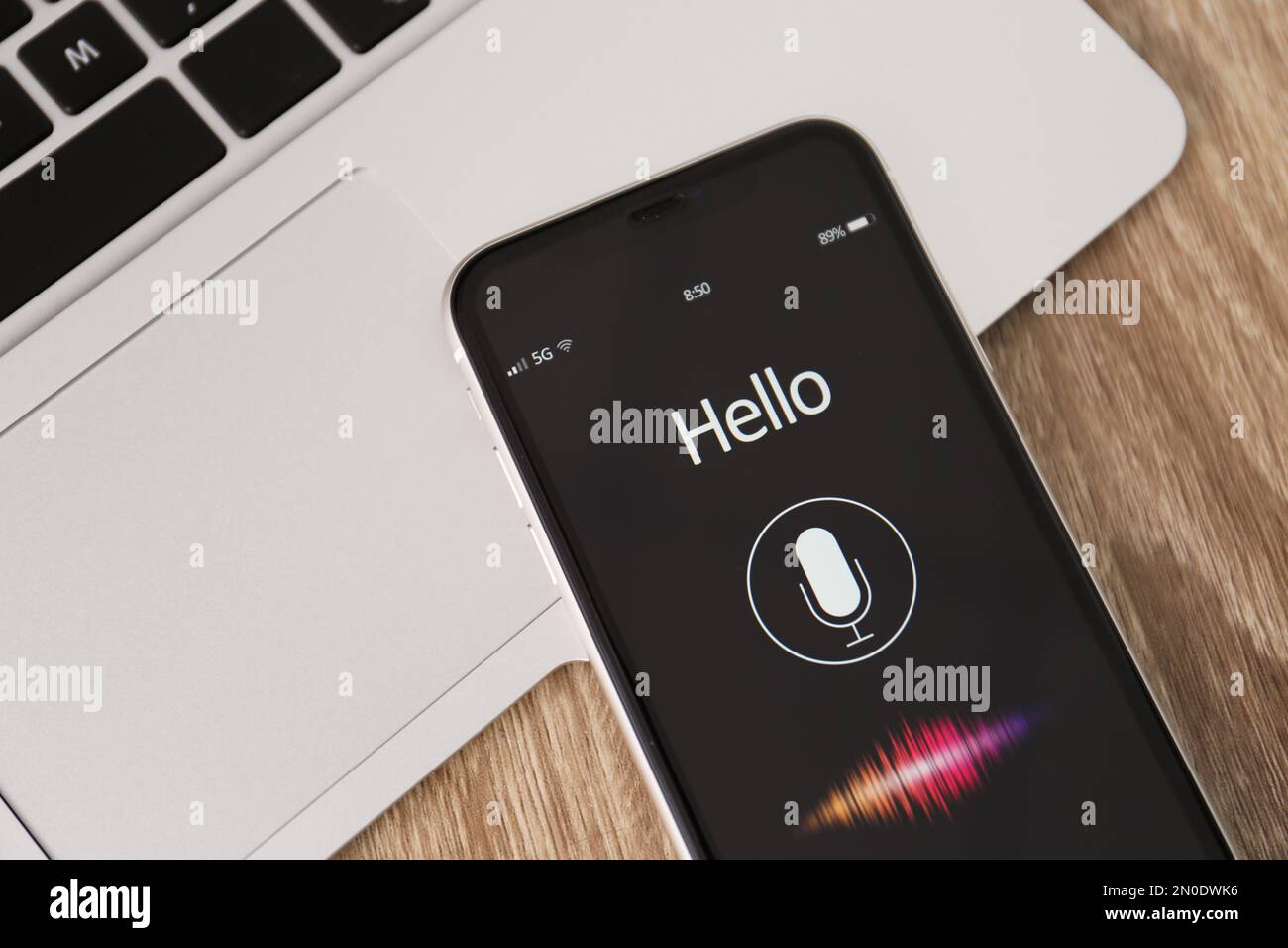 Smartphone with activated voice search app and laptop on wooden table, closeup Stock Photo