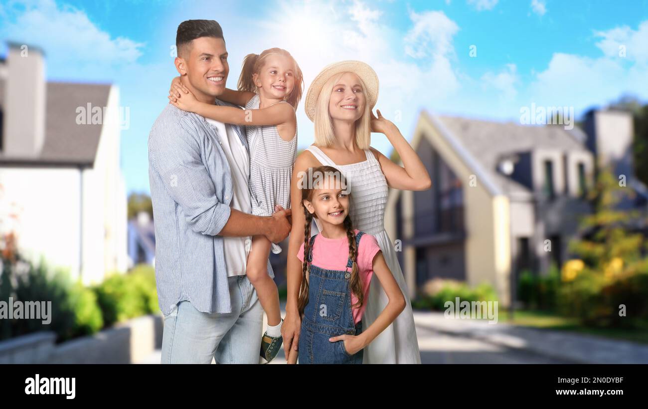 Happy family standing in front of their house on sunny day Stock Photo