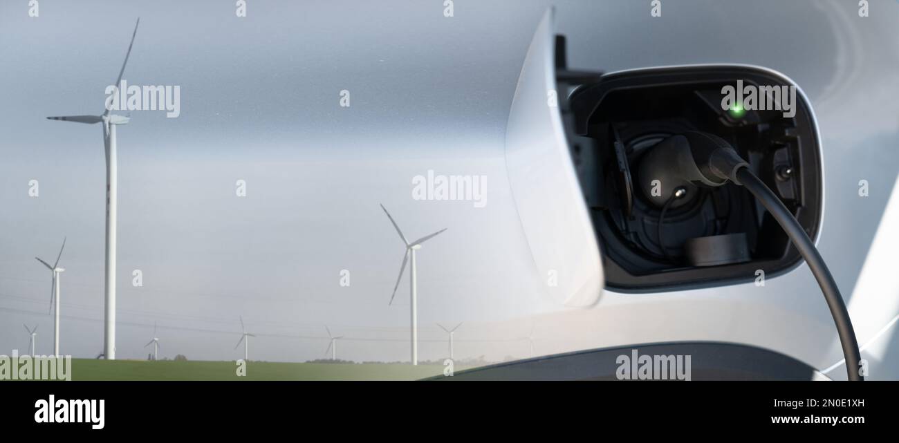 Close up of electric car inlet with a connected charging cable and double exposure with wind
