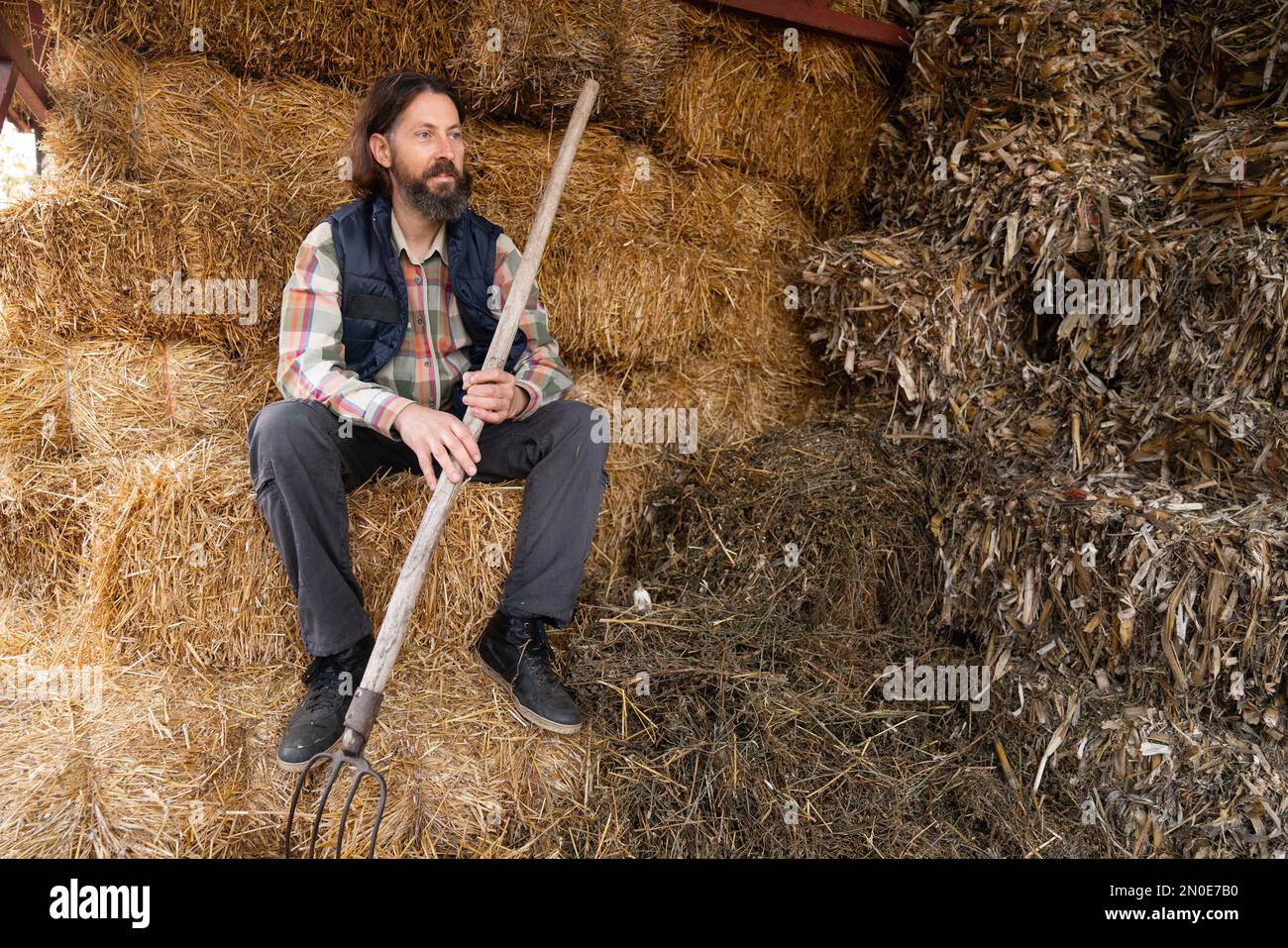 Bearded adult caucasian farmer in the hayloft. Stock Photo