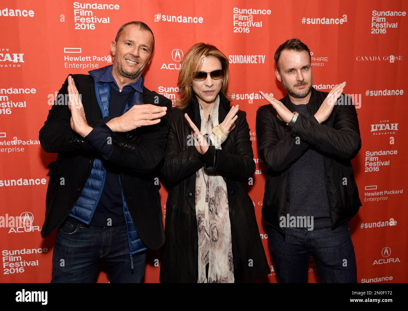 Yoshiki, center, cofounder of the Japanese heavy metal band X Japan, makes the X symbol with