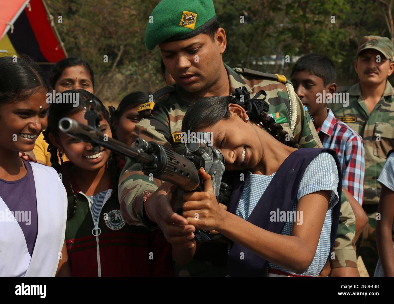 Students listen as an Indian army soldier demonstrates the use of a weapon at a display of arms