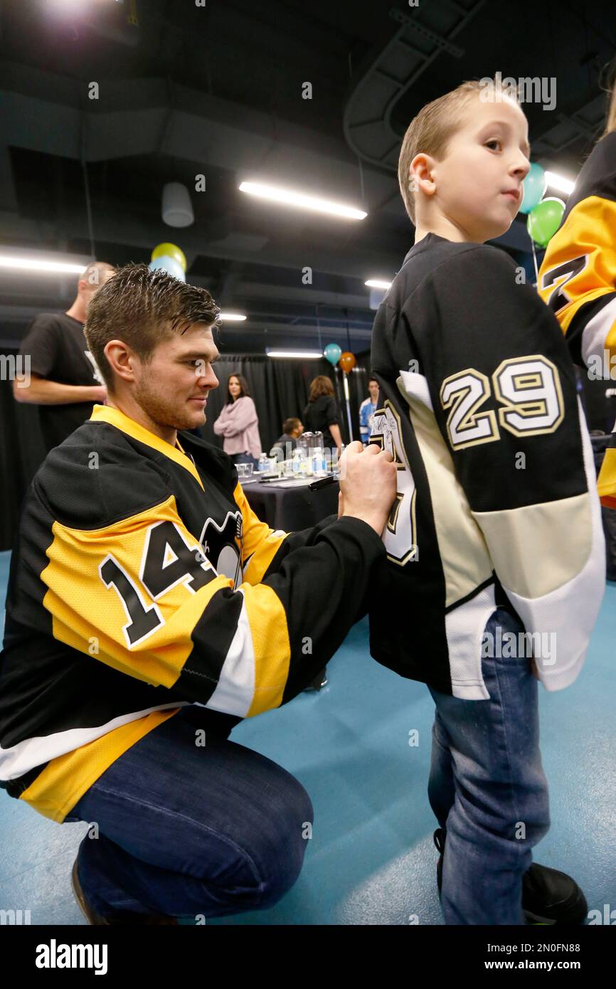 Pittsburgh Penguins Chris Kunitz 14 signs an autographs on the jersey of 7 year old Ryan Spitznatel at the the Penguins Local Children s Charities Annual Practice Party after their NHL hockey practice...