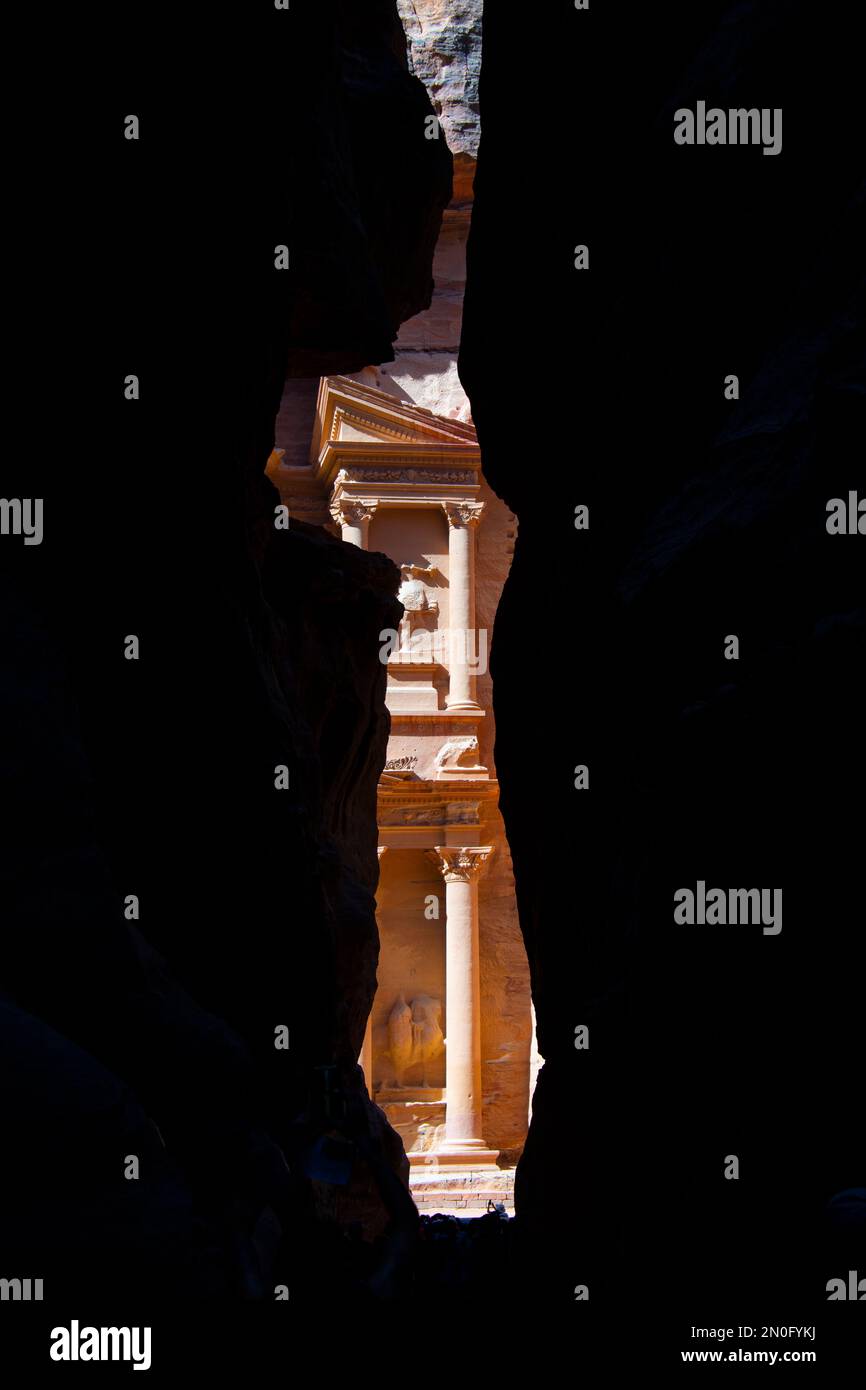 Behind the huge rocks of stone appears the beautiful monument of Petra Stock Photo