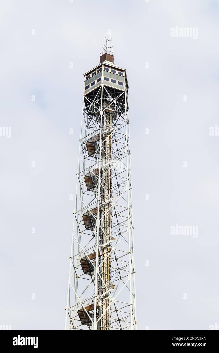 A fire watch tower with a wooden house on top of it against a light