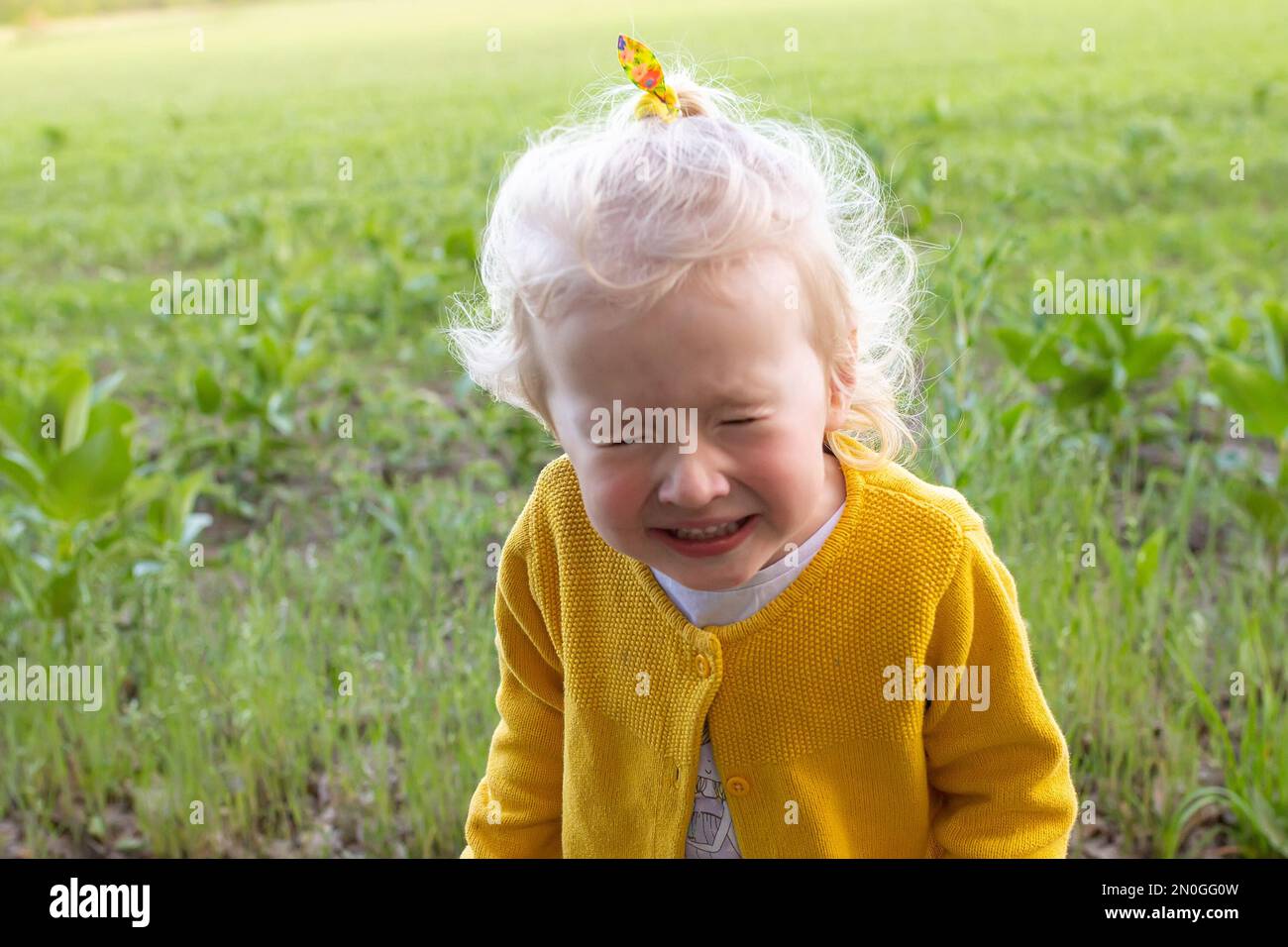 Girl in yellow jacket sneezed. child on background of a summer field