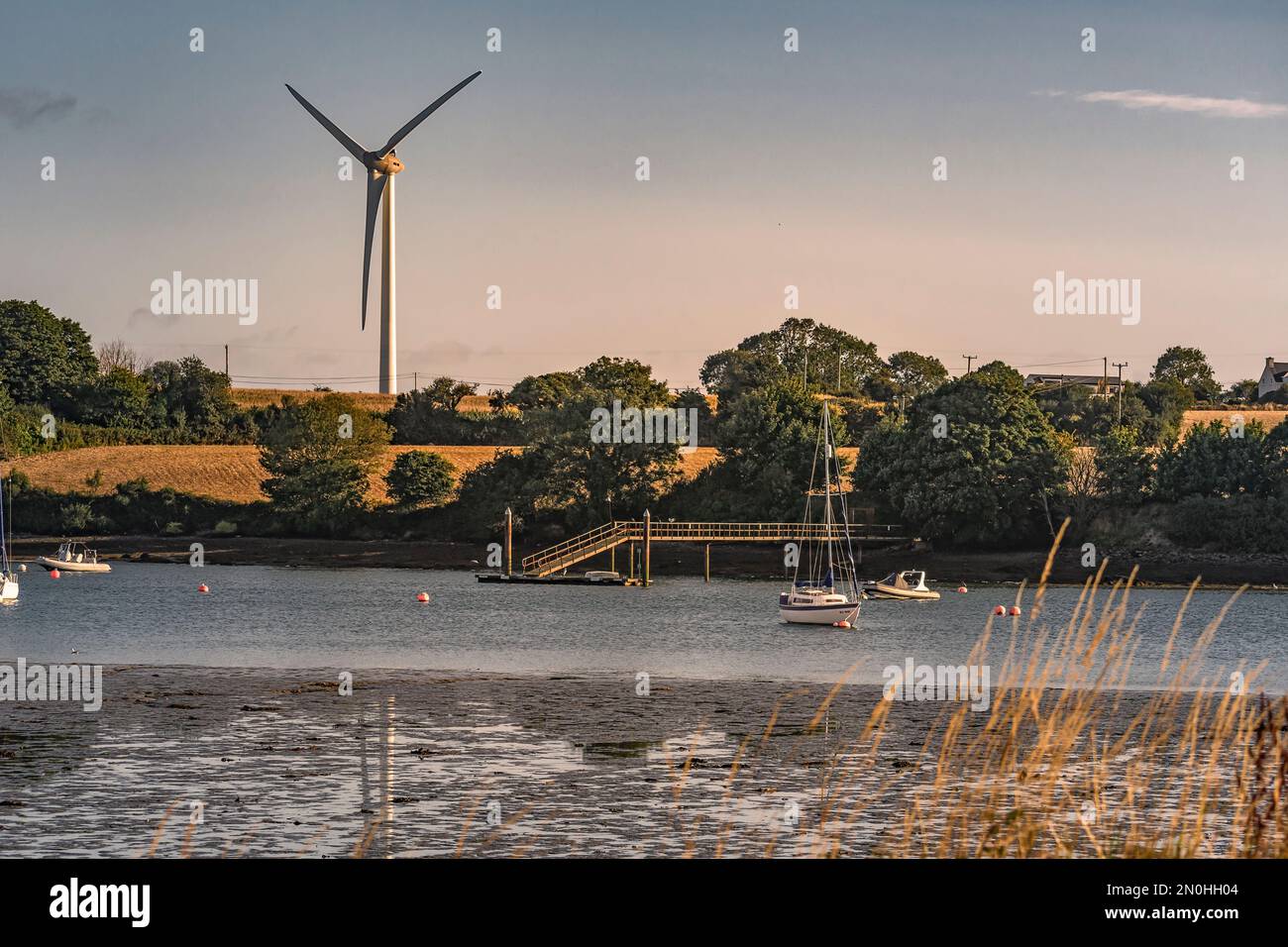 Sailing boat anchorage at Owenabue river estuary with wind generator turbines in the background. Ireland Stock Photo