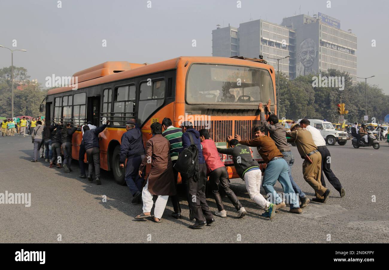 Passengers and traffic policemen push a bus after it broke down at a ...