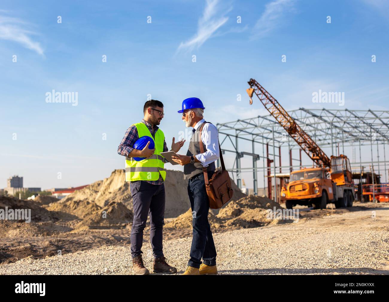 Senior and young engineers talking about project at building site Stock Photo