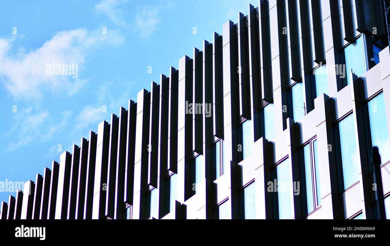 Blue sky and clouds reflected in windows of modern office building ...