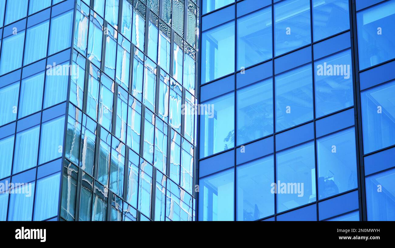 Blue sky and clouds reflected in windows of modern office building ...