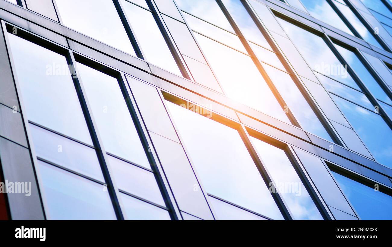 Blue sky and clouds reflected in windows of modern office building ...