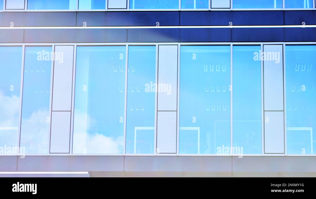 Blue sky and clouds reflected in windows of modern office building ...
