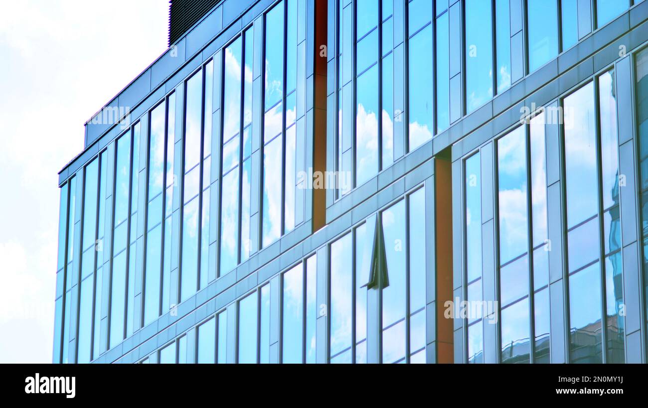 Blue sky and clouds reflected in windows of modern office building ...