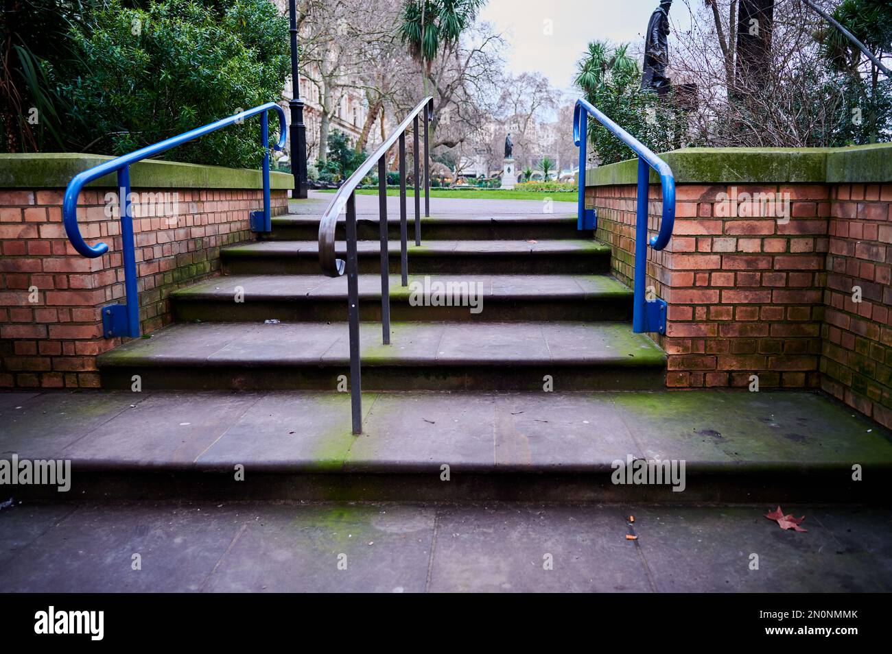 steps with metal railing and red brick wall to park Stock Photo