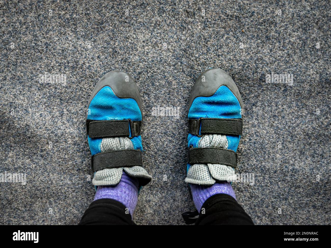Close up of feet wearing indoor climbing wall shoes standing on soft