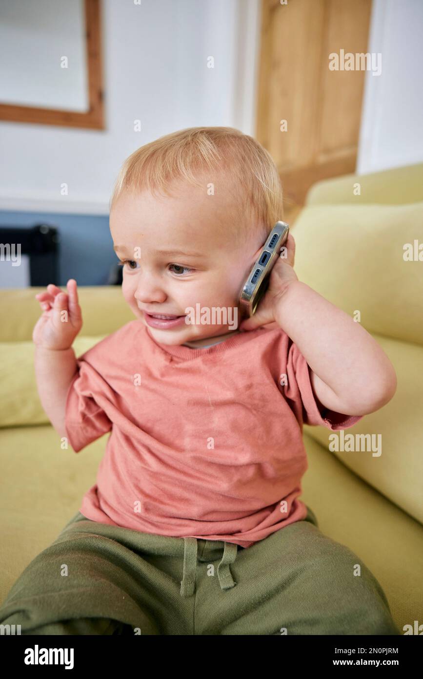 Toddler holding smart phone with animated expression indoors Stock Photo