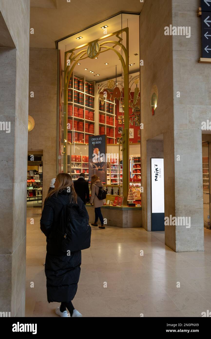 Maxims store in Paris at le Louvre delicious Macarons and Chocolats. Refined and good taste store. Paris food stores. Woman walking on shopping. Stock Photo