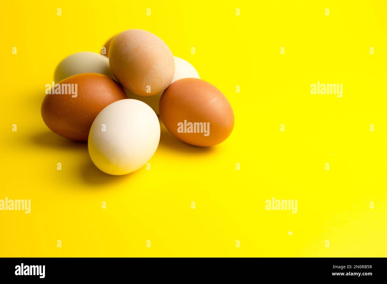 different color Free range chicken Eggs on a yellow background Stock Photo