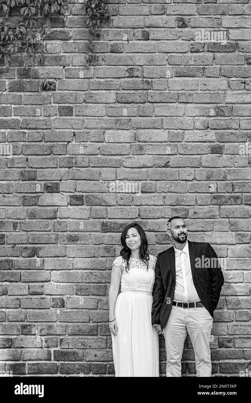 Couple standing against brick wall in black and white Stock Photo Alamy